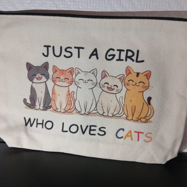 Pochette beige à fermeture zippée, illustrée de cinq chats souriants et de l’inscription « Just a girl who loves cats ».