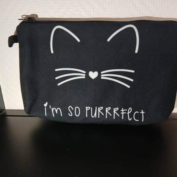 Pochette en tissu noir avec un visage de chat souriant, un nez en forme de cœur et l’inscription « I'm so purrrfect ».